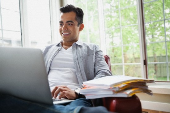 Man using laptop while sitting on couch at home.